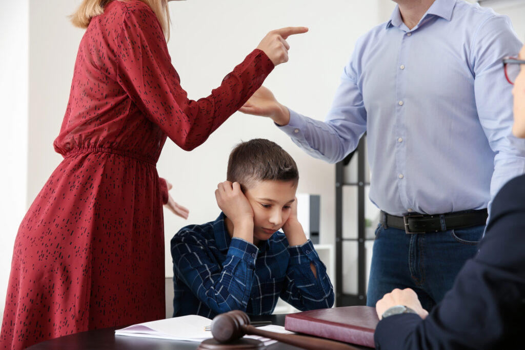 Sad little boy with his quarreling parents in lawyer's office