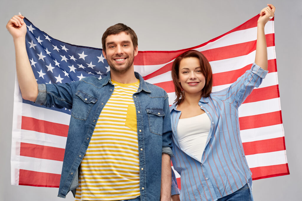 Man and woman holding the American flag behind them while smiling