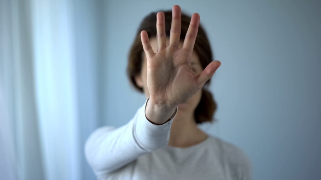 Exhausted frightened woman showing stop sign