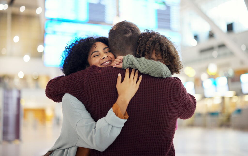 Family hugging in an airport after international trip